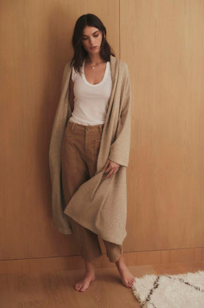 A woman wearing a Velvet by Graham & Spencer PATRICIA DOUBLE KNIT DUSTER CARDIGAN standing in front of a wooden wall.