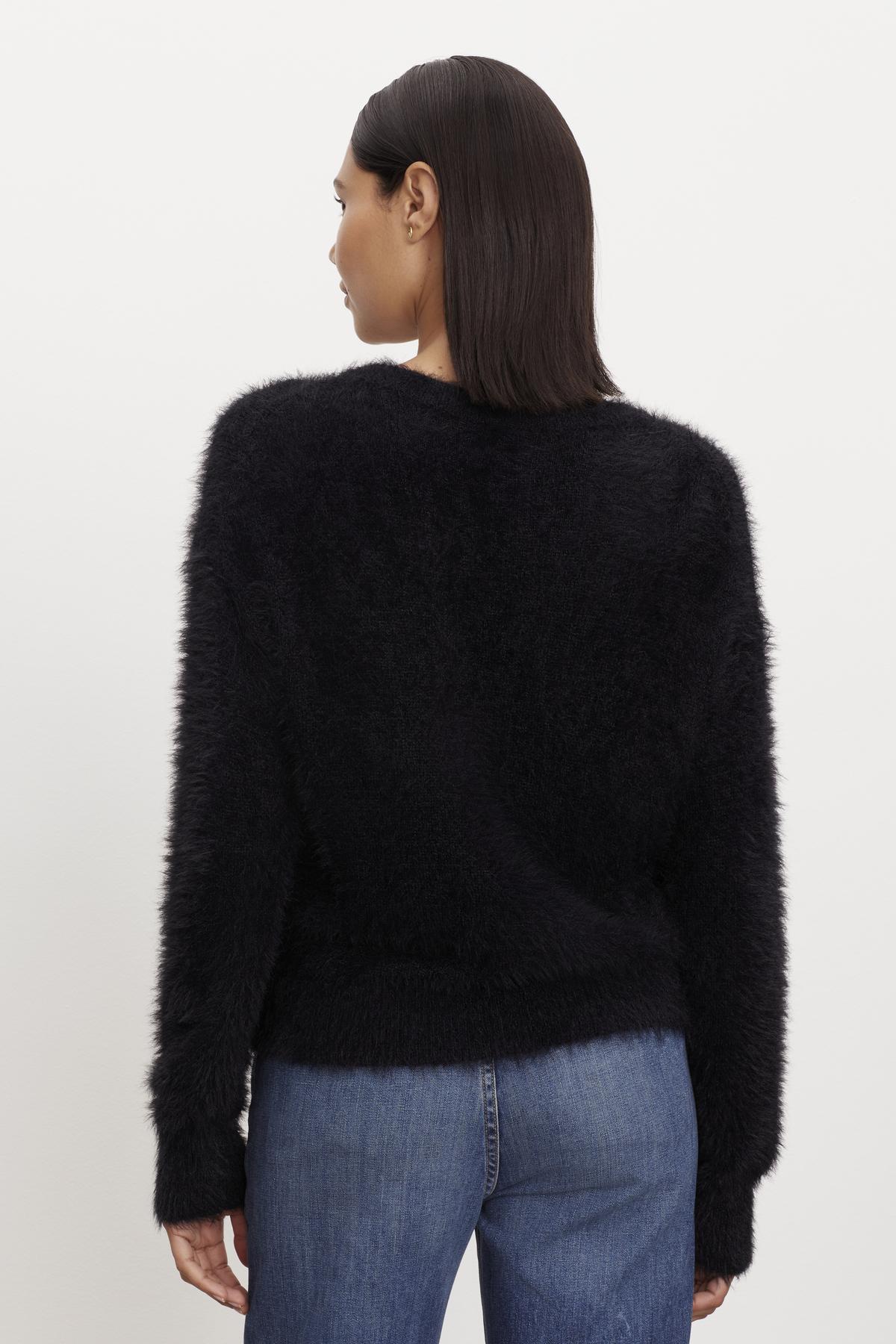 The back view of a person wearing a KELSEY FEATHER YARN CARDIGAN by Velvet by Graham & Spencer with ribbed trims.