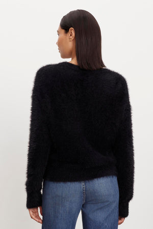 The back view of a person wearing a KELSEY FEATHER YARN CARDIGAN by Velvet by Graham & Spencer with ribbed trims.