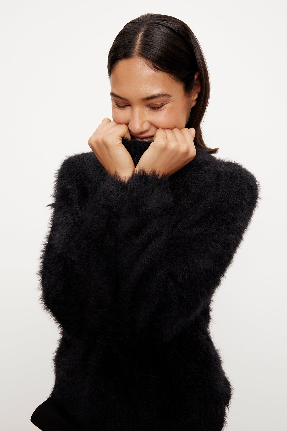 A woman wearing a Velvet by Graham & Spencer Ray Feather Yarn Crew Neck Sweater adds a touch of luxe edge to holiday gatherings.-35572015694017