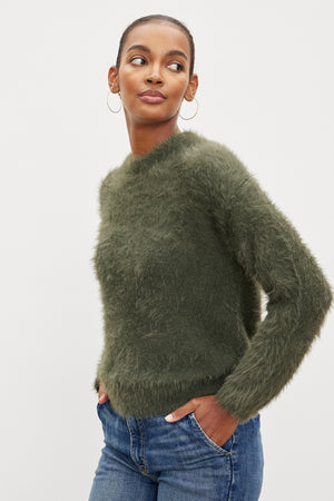 A model wearing a green Velvet by Graham & Spencer RAY FEATHER YARN CREW NECK SWEATER and jeans.