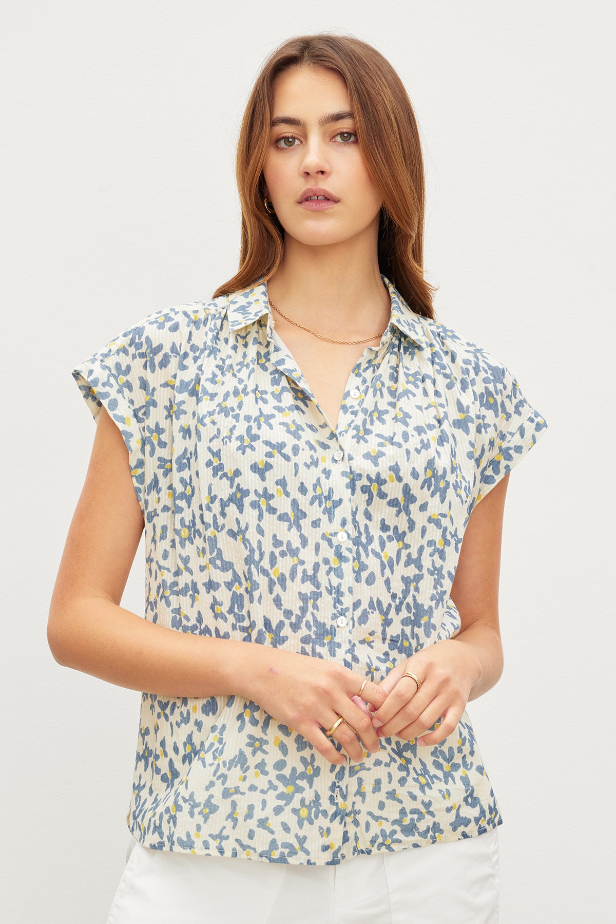 A woman wearing a Velvet by Graham & Spencer PAULETTE FLORAL BUTTON FRONT TOP with subtle stripe details.-35967566250177