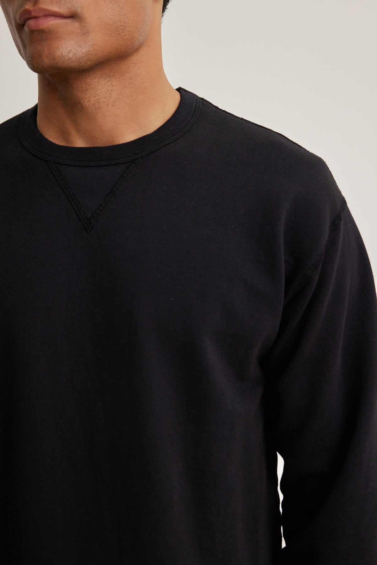 A person wearing the RAE SWEATSHIRT by Velvet by Graham & Spencer, a plain black French terry crew neck, is shown from shoulders to mid-torso, facing forward.-39152732340417