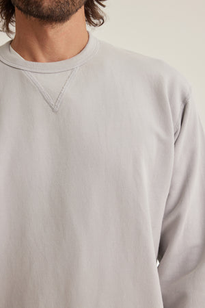 A person wearing the RAE SWEATSHIRT by Velvet by Graham & Spencer, a light gray crewneck with visible stitching and a classic neckline, shown from shoulders to mid-chest.