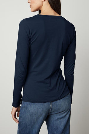 Person with long dark hair wearing a navy blue fitted long sleeve Velvet by Graham & Spencer ZOFINA TEE and jeans, shown from the back.