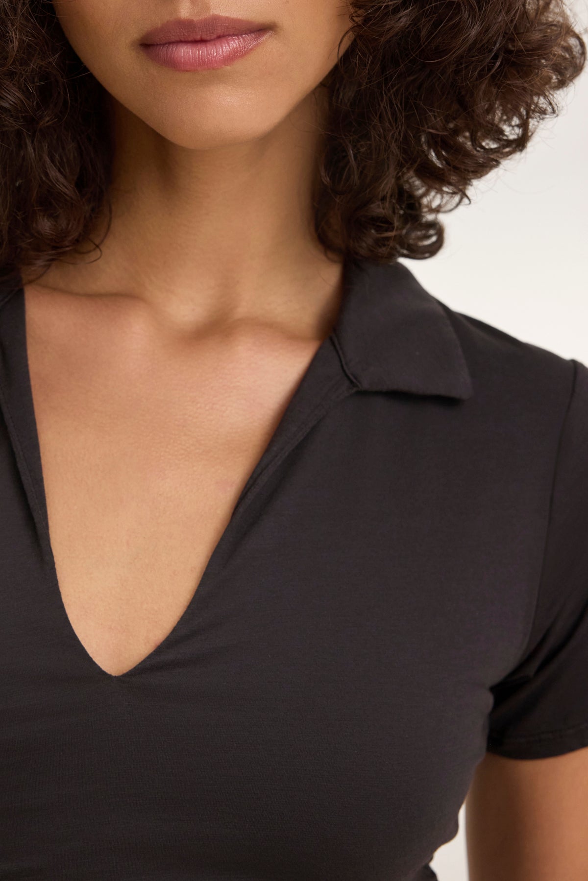 Dressed in an ANDEE DRESS by Velvet by Graham & Spencer, a person with cascading curly hair stands against a neutral background, exuding effortless style akin to a whisper cotton.