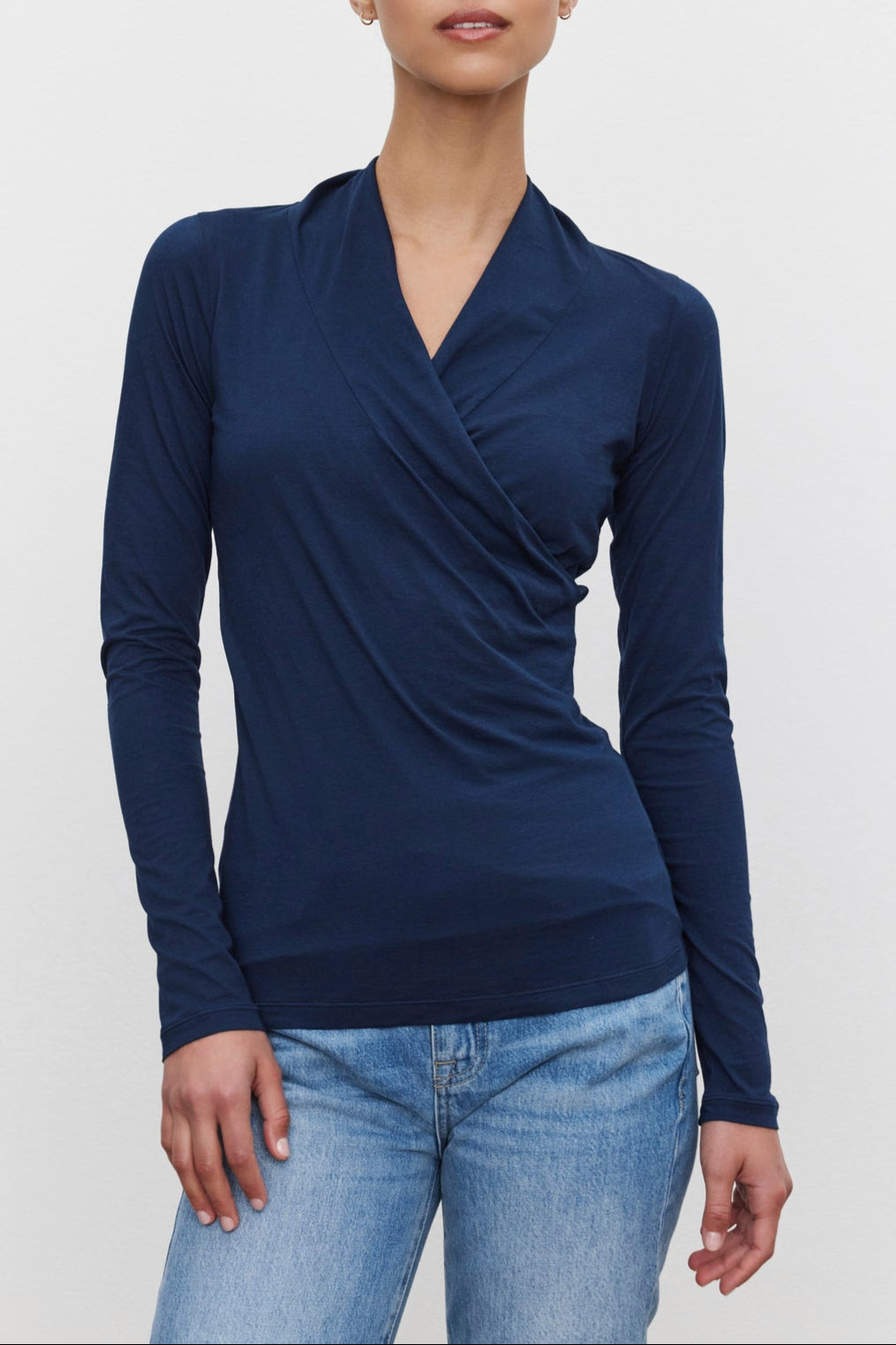 A person wearing a navy blue long-sleeved MERI TEE by Velvet by Graham & Spencer and blue jeans stands against a white background.-37856497500353