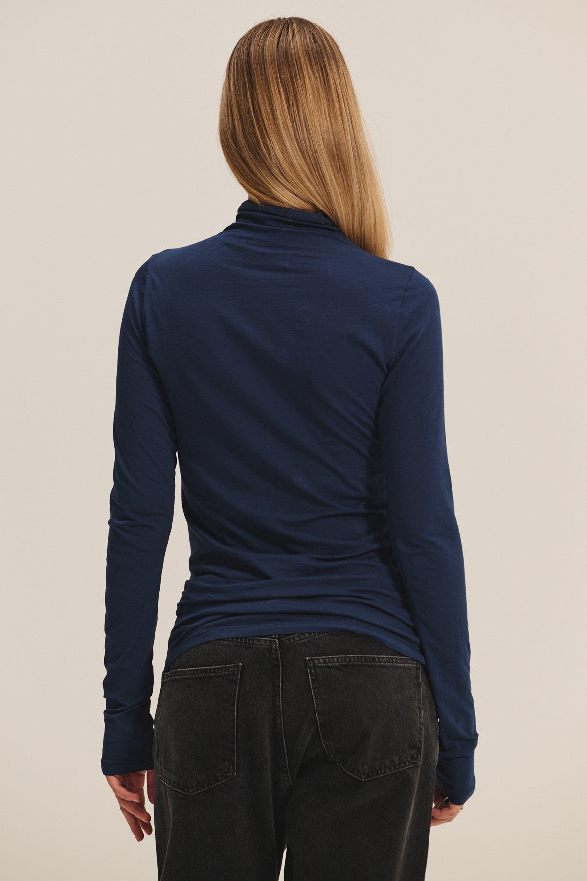 A person with long, straight hair wears the TALISIA TEE by Velvet by Graham & Spencer in navy blue, paired with black jeans and shown from the back against a plain background—an effortlessly chic wardrobe staple.-40252512338113