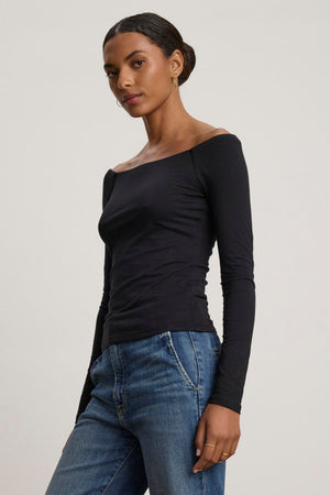 A person wearing the TANYA TEE by Velvet by Graham & Spencer and blue jeans, standing against a plain background.