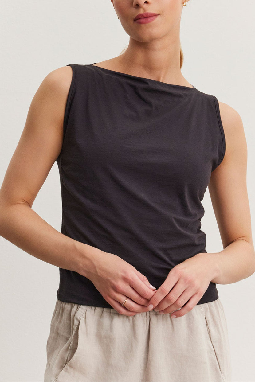 A woman with blonde hair, wearing a Velvet by Graham & Spencer EMILIA tank top and beige pants, stands against a white background, looking directly at the camera.