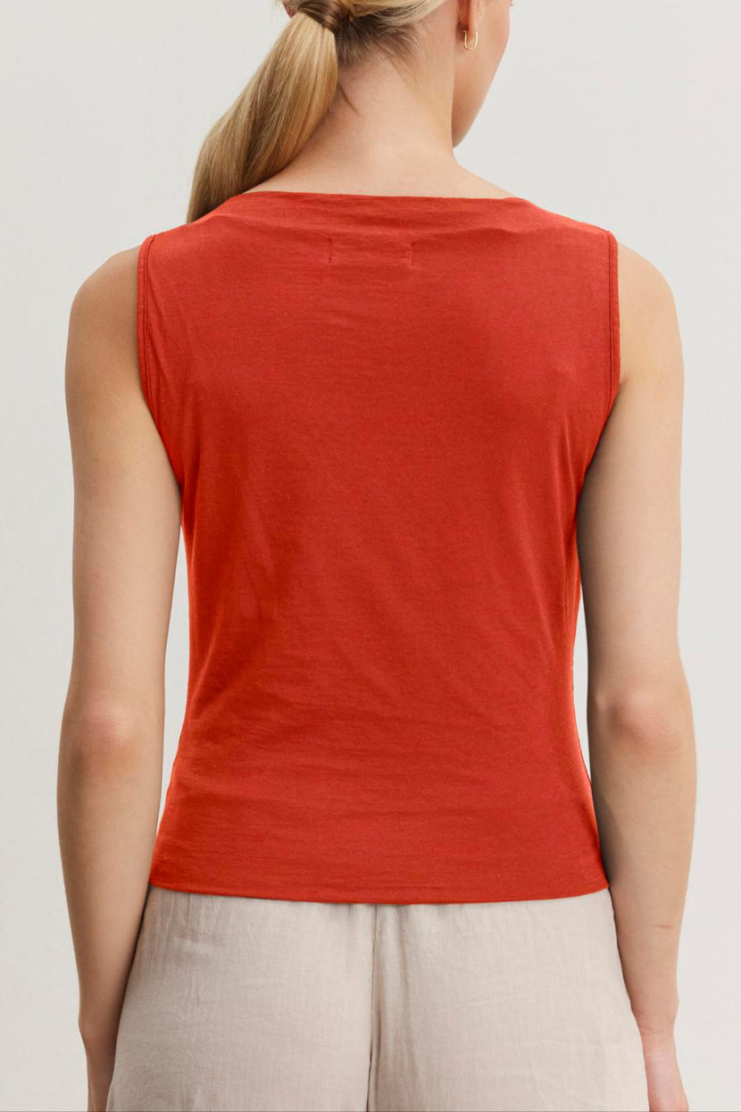 A person with blond hair tied in a low ponytail is shown from the back, wearing a Velvet by Graham & Spencer EMILIA TANK TOP and beige pants.