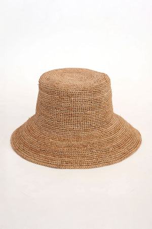 The CHIC CROCHET BUCKET HAT by Velvet by Graham & Spencer is a brown straw hat crafted from natural raffia, featuring a wide flared brim for excellent sun protection. Set against a plain white background, it beautifully combines style and practicality.