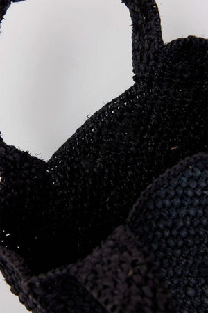 Close-up of the MINI LULU TOTE, a black woven basket by Velvet by Graham & Spencer, featuring two handles against a plain background.