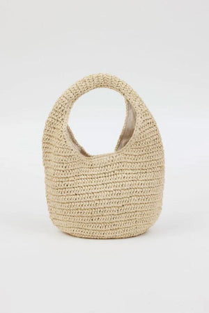 The SHELLY BAG by Velvet by Graham & Spencer is a small woven straw handbag featuring a circular handle, shown against a plain white background.