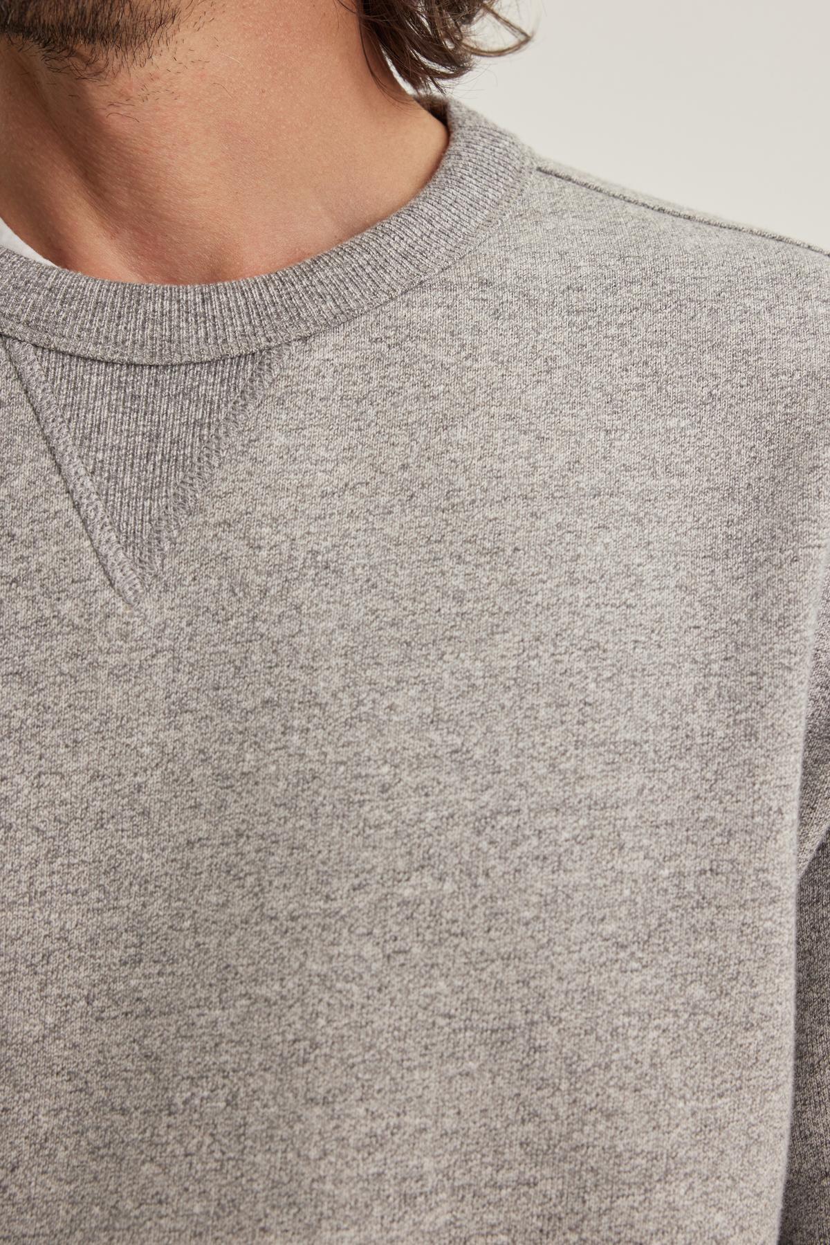 Close-up of someone wearing the HAMES SWEATSHIRT by Velvet by Graham & Spencer. The shoulder and upper chest are visible in this grey crewneck sweater.-38643296665793
