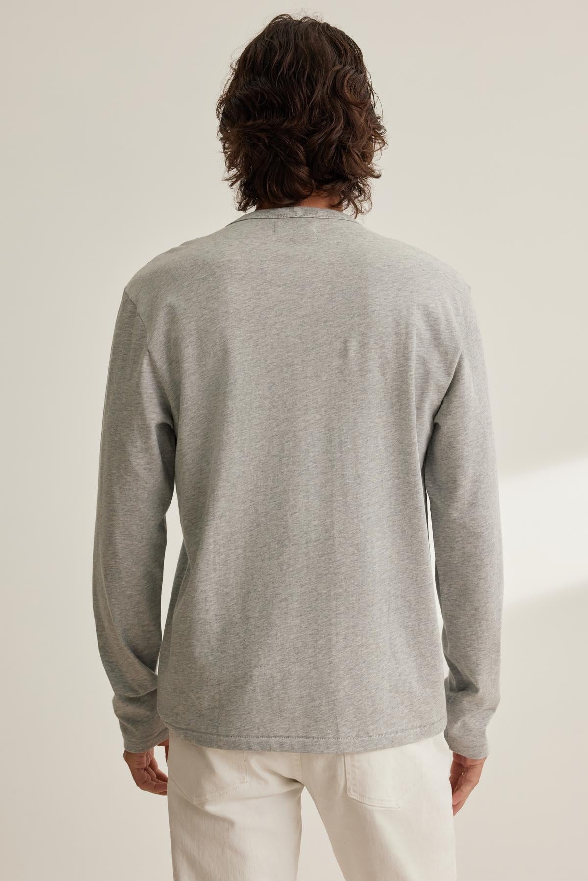 A person with shoulder-length hair is seen from the back wearing a gray EVREN TEE by Velvet by Graham & Spencer with white pants, against a light background.-38643282804929
