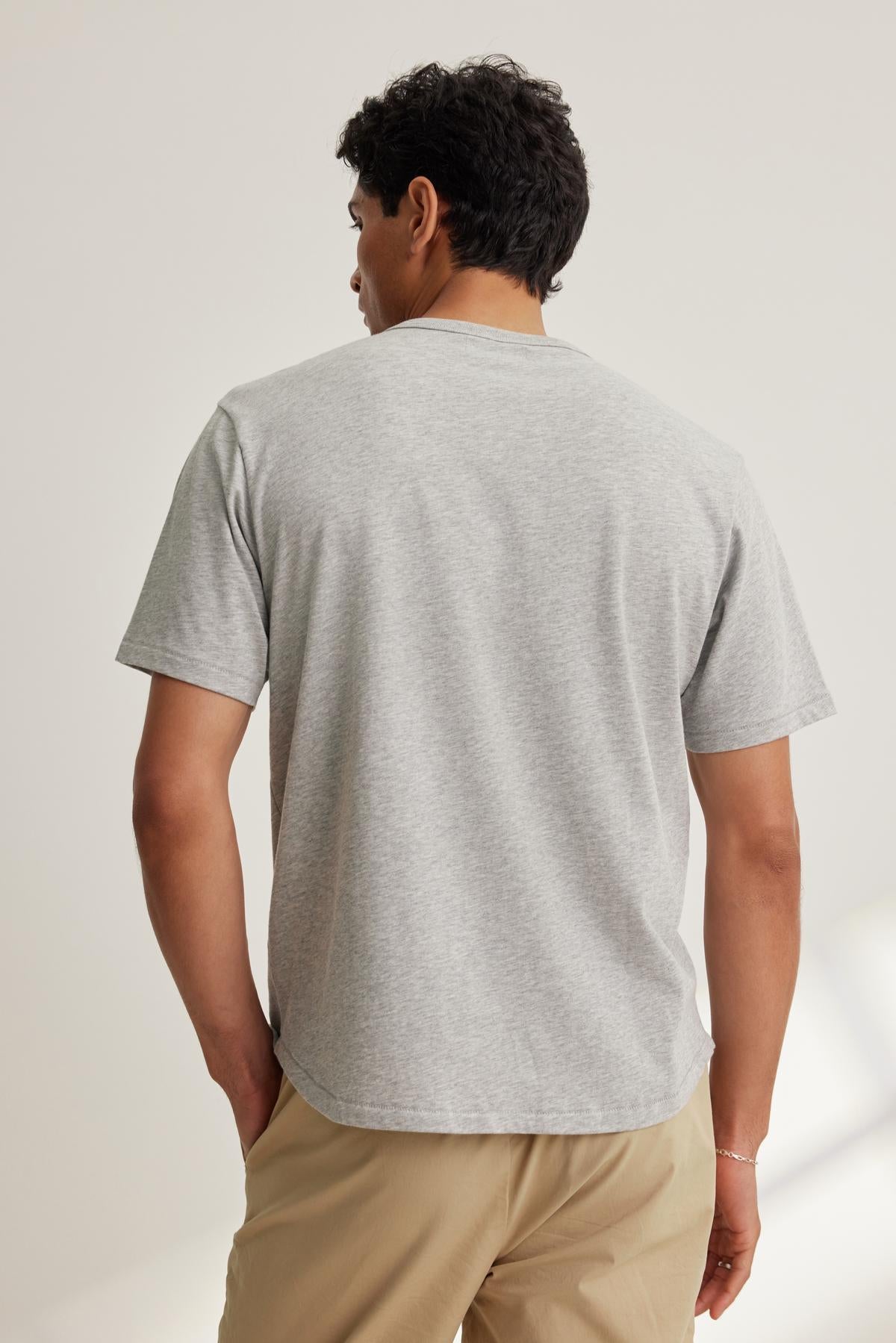 A person is shown from the back wearing the Velvet by Graham & Spencer MADDEN TEE in gray and beige pants against a plain background.