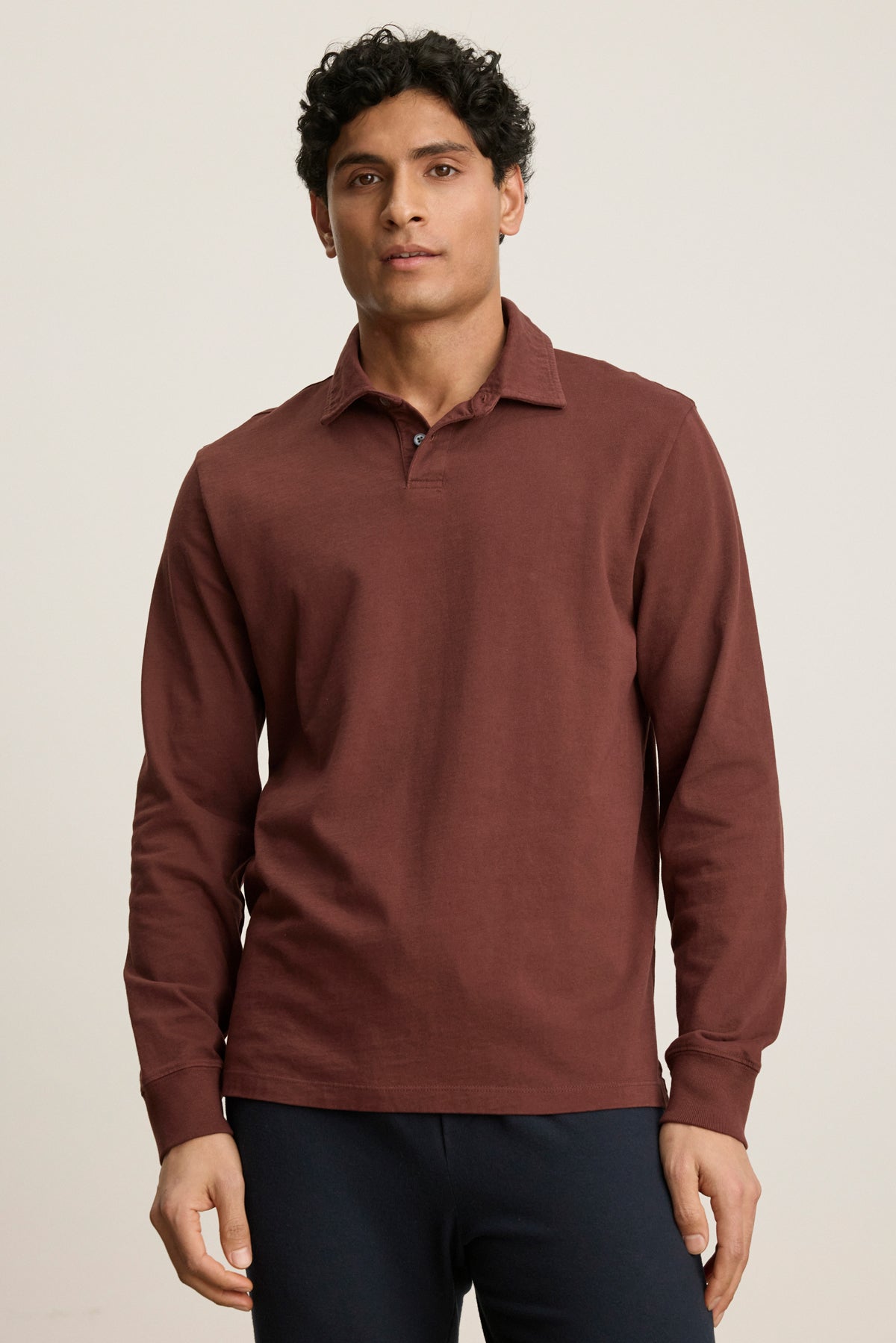 A man stands facing forward against a plain light background, wearing the HAWKINS POLO by Velvet by Graham & Spencer—a tailored fit polo with a classic two-button placket—paired with dark pants.
