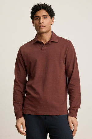 A man stands facing forward against a plain light background, wearing the HAWKINS POLO by Velvet by Graham & Spencer—a tailored fit polo with a classic two-button placket—paired with dark pants.