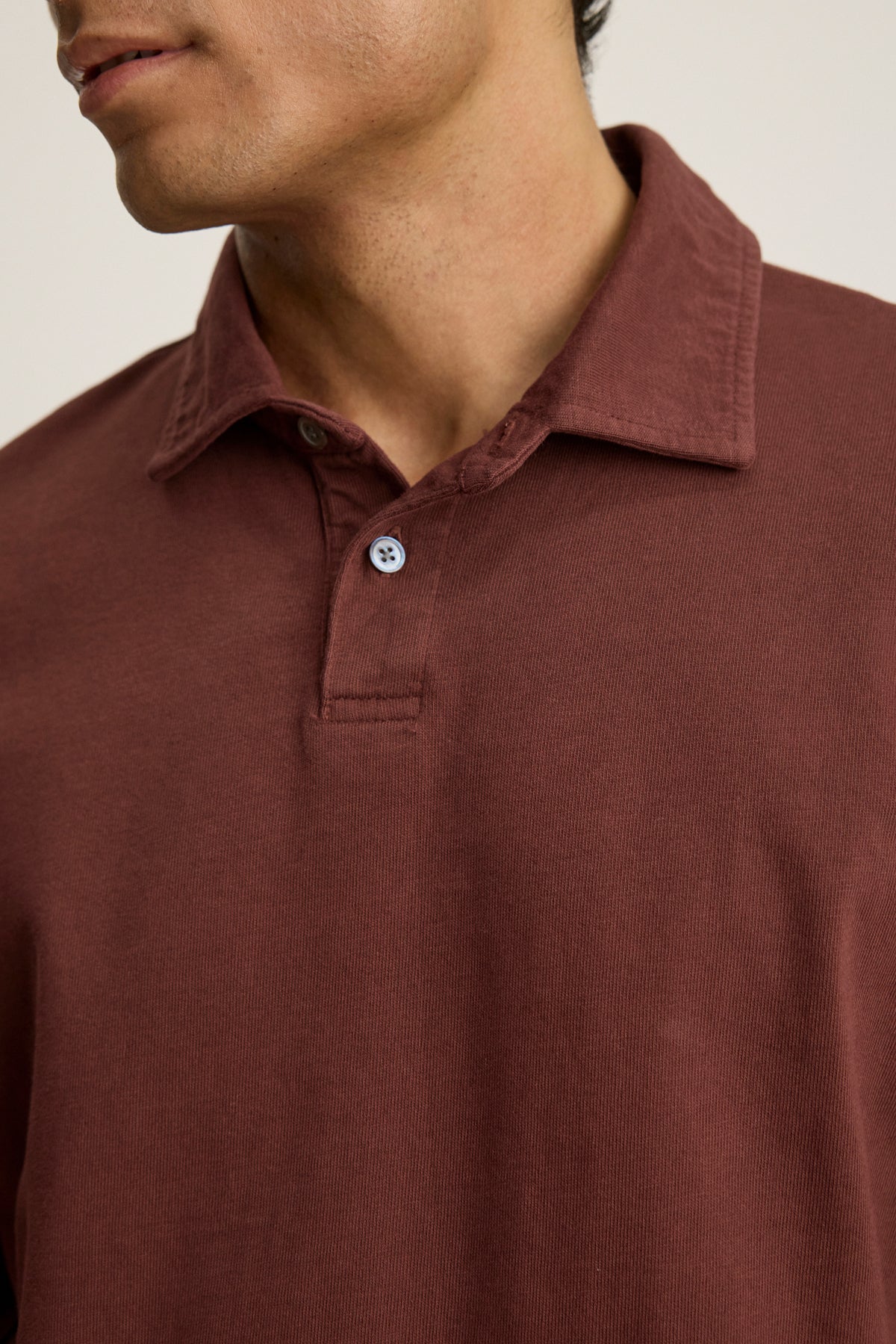 A person wears the HAWKINS POLO by Velvet by Graham & Spencer—a maroon tailored-fit polo with a classic two-button placket; only the lower half of the face and upper torso are visible.