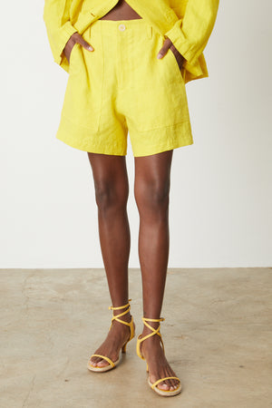 A woman wearing Velvet by Graham & Spencer's FALLON HEAVY LINEN SHORT and sandals with zipper closure.