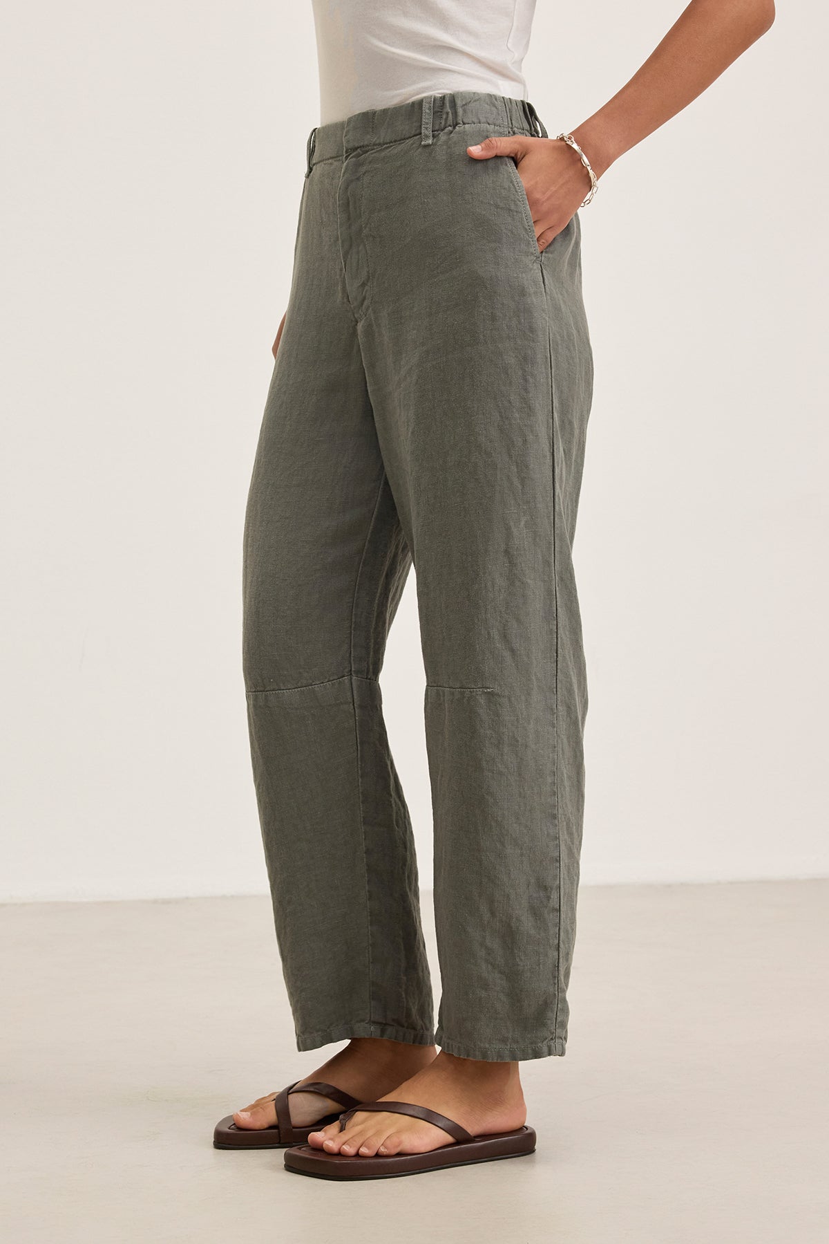 A person in TAYLOR HEAVY LINEN PANT by Velvet by Graham & Spencer, a white top, and black sandals stands with one hand on their hip against a neutral background.
.-38663166492865