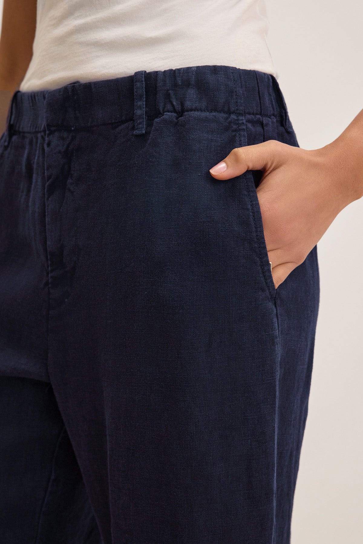 Someone wearing Velvet by Graham & Spencer's TAYLOR HEAVY LINEN PANT in navy with a barrel leg, paired with a white top and one hand casually in the pocket.-41645170458817