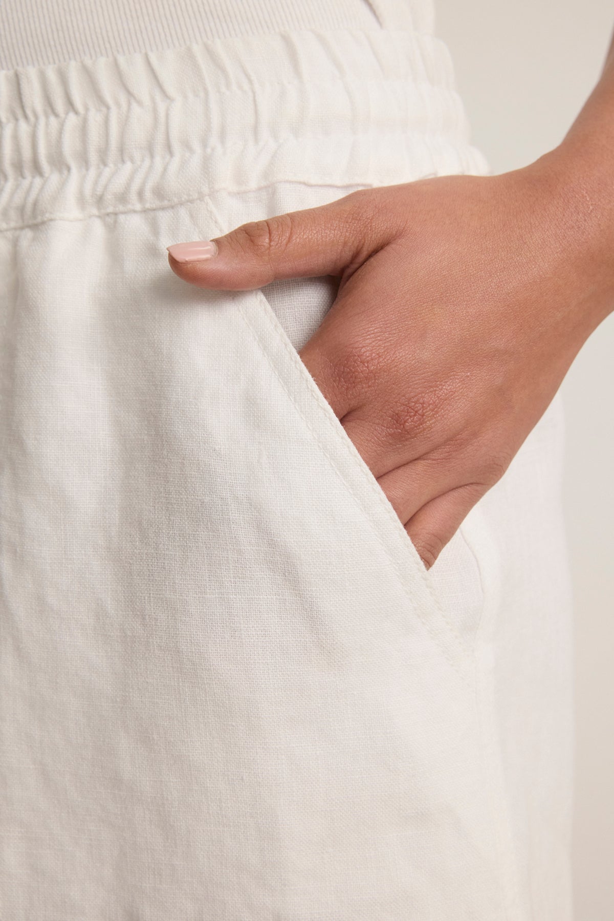 A close-up of a hand in the side pocket of Velvet by Graham & Spencer’s SUTTON HEAVY LINEN SHORT—white, relaxed fit, elastic-waist shorts that are a true warm-weather essential.-39123355861185