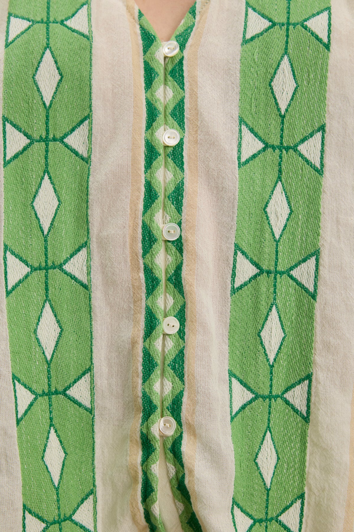 Close-up of the MARISSA TOP by Velvet by Graham & Spencer, a cotton jacquard V-neck with vertical green and white geometric patterns, puff sleeves, and a row of white center buttons.