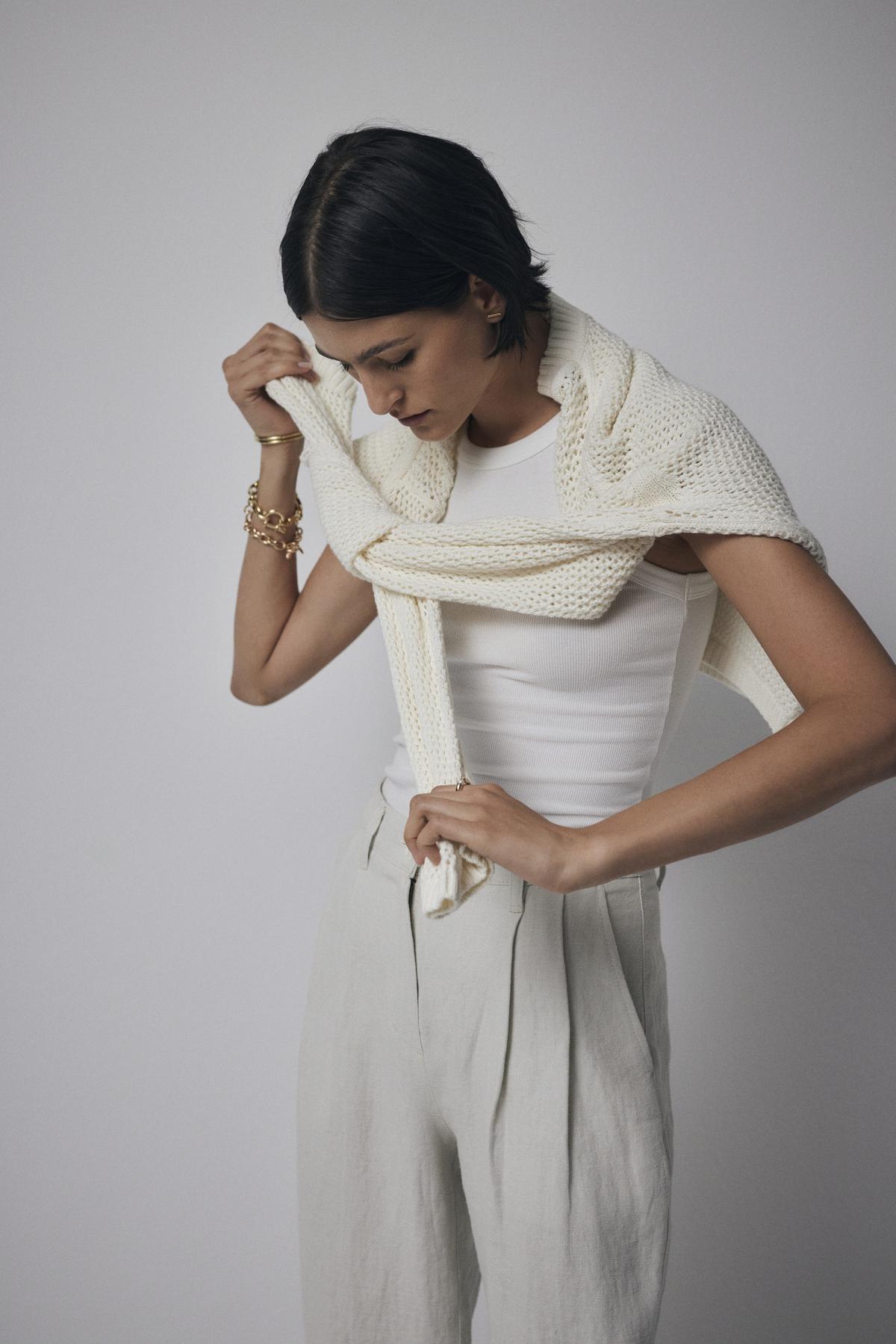   A woman wearing a lightweight white cotton cashmere blend KANAN sweater by Velvet by Jenny Graham. 