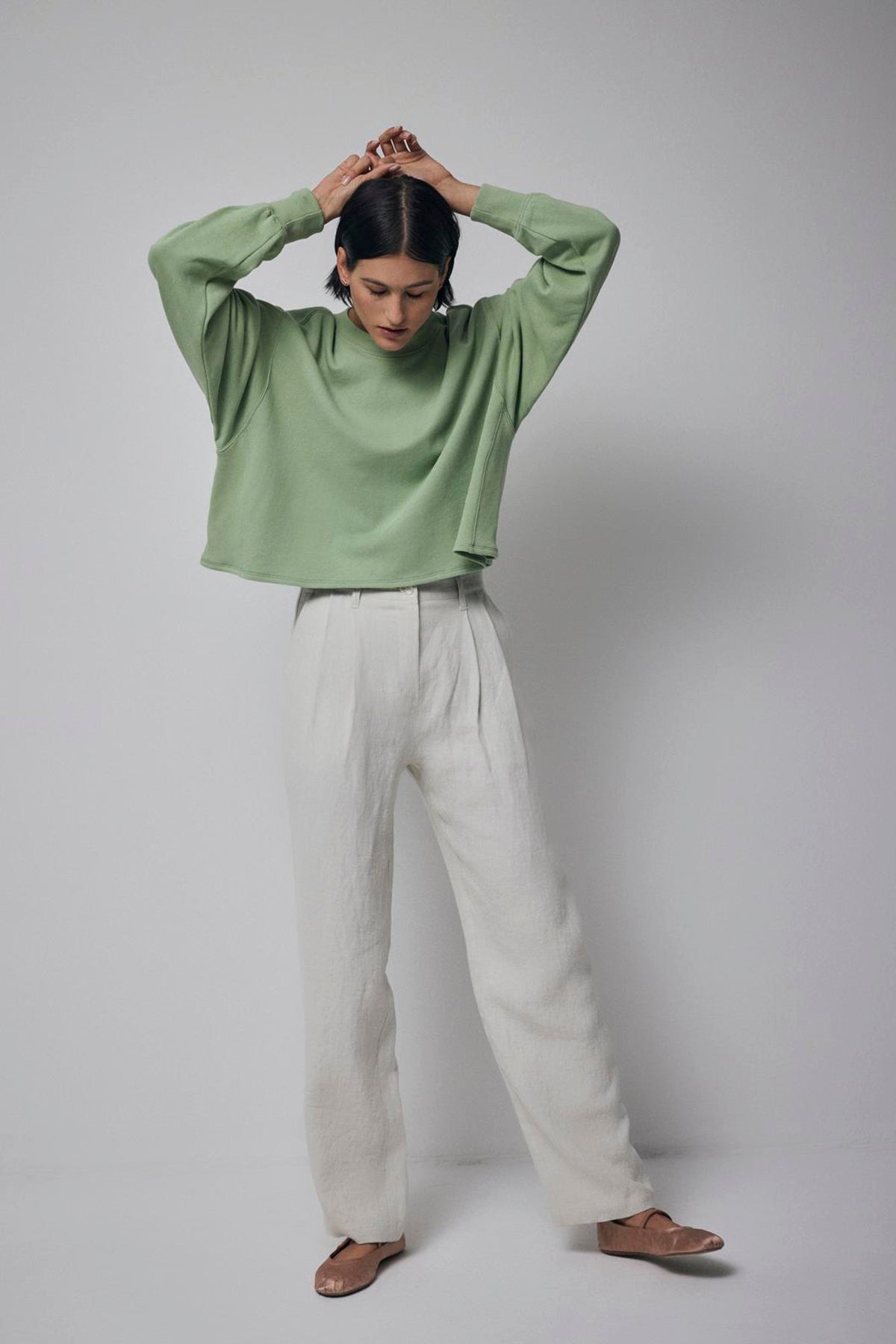   A woman wearing a green Velvet by Jenny Graham MALIBU SWEATSHIRT and white pants. 