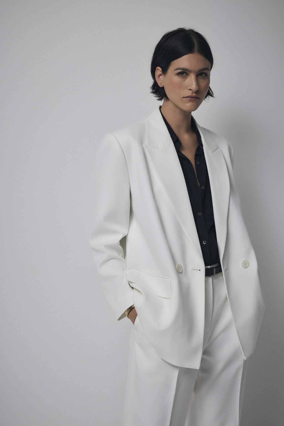   A woman wearing a structured white Fairfax blazer by Velvet by Jenny Graham and black pants. 