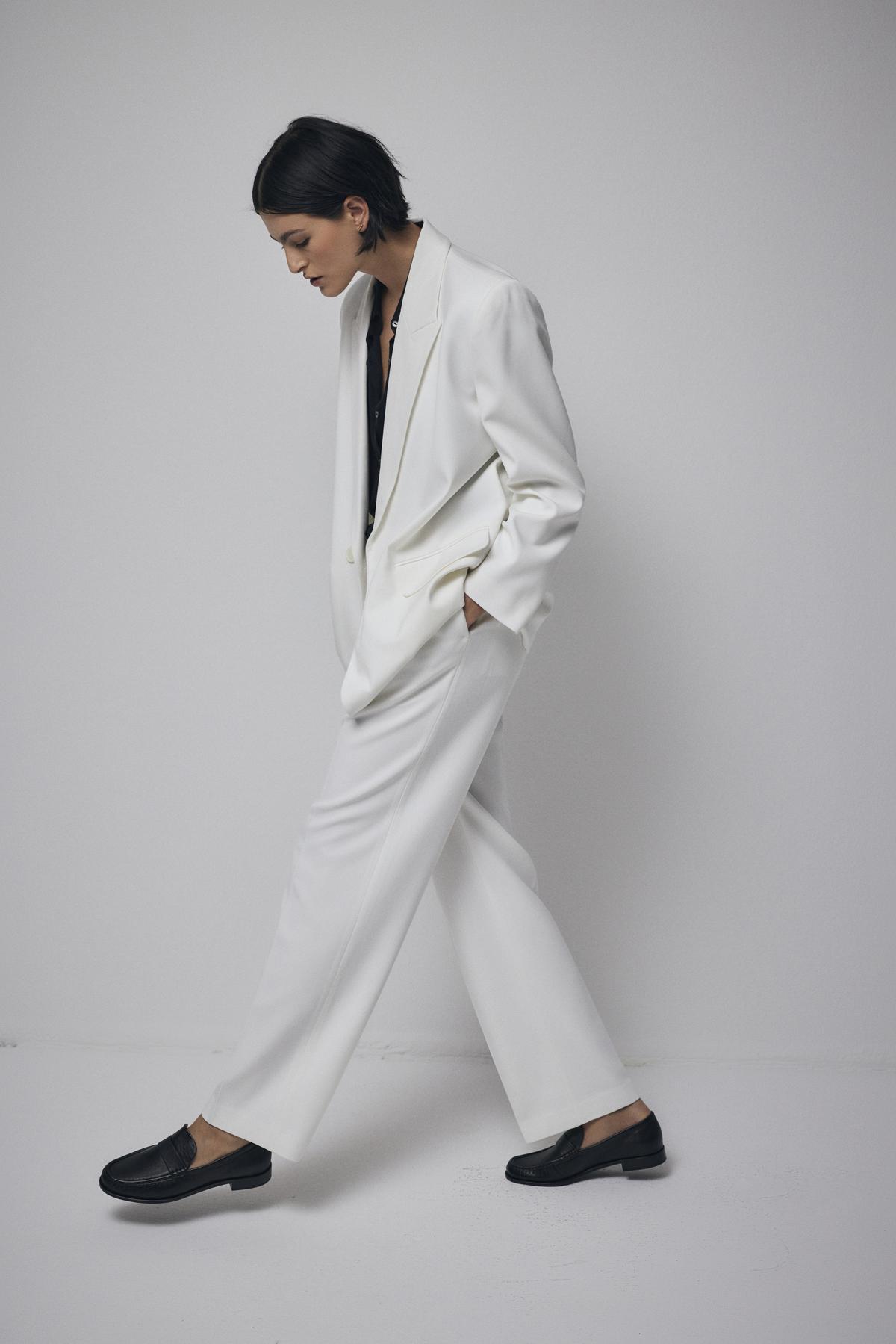   A woman wearing a white structured Fairfax blazer by Velvet by Jenny Graham with black shoes. 