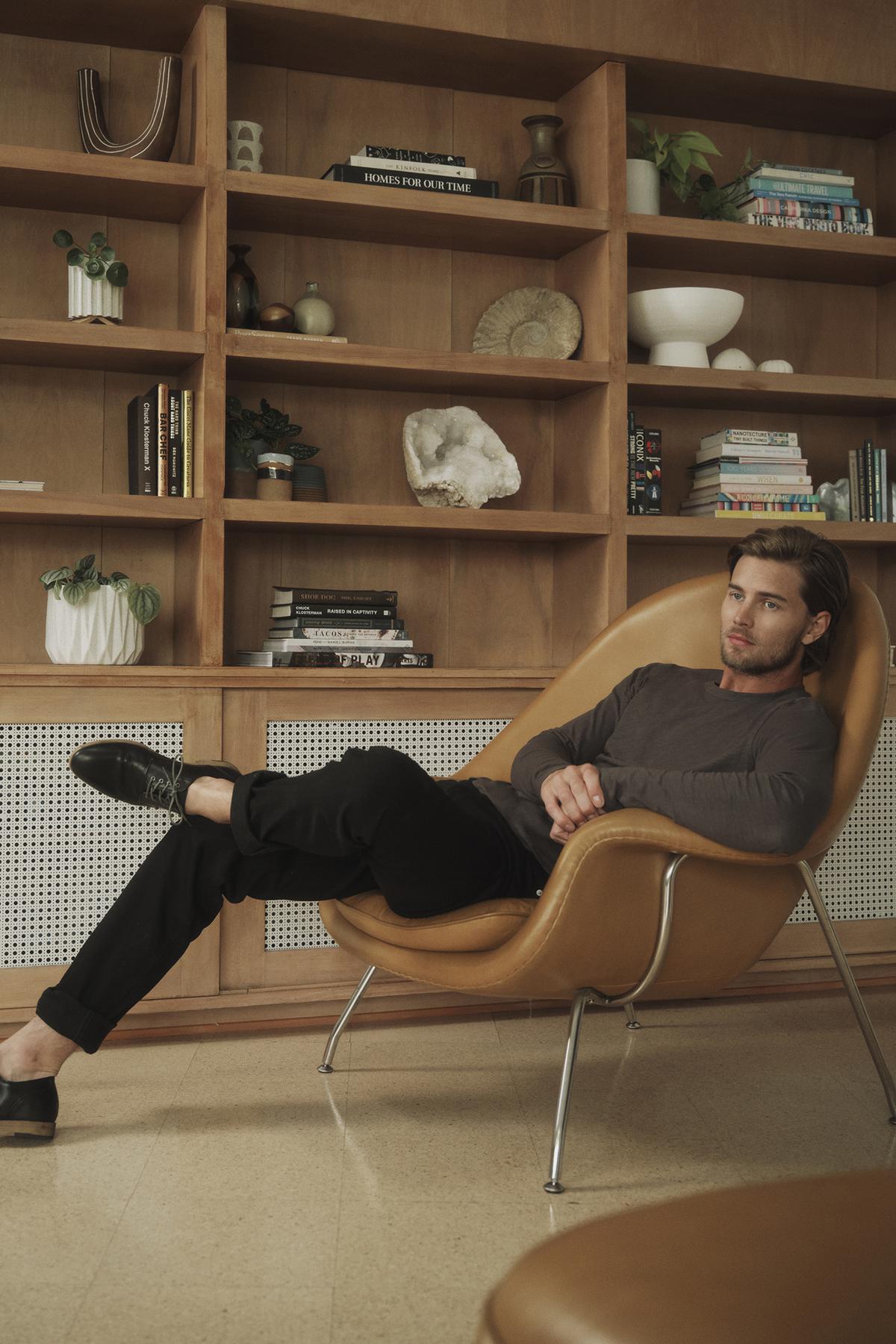 A man is sitting on a chair in front of a bookcase wearing the Velvet by Graham & Spencer KAI CREW NECK TEE.-35782958809281
