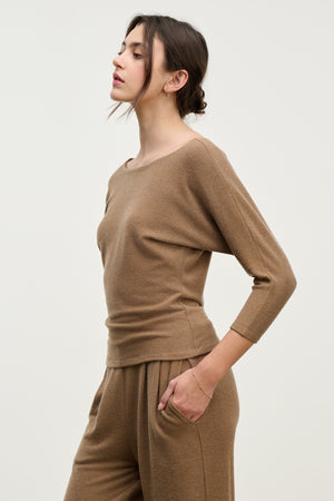 Woman in profile wears the SELENA TOP by Velvet by Graham & Spencer—a light brown, long-sleeve cotton-viscose top with a relaxed fit—paired with matching pants, set against a plain light background.