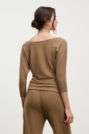 A woman with her hair tied back stands facing away, showcasing the relaxed silhouette of the SELENA TOP by Velvet by Graham & Spencer in brown, paired with matching pants.
