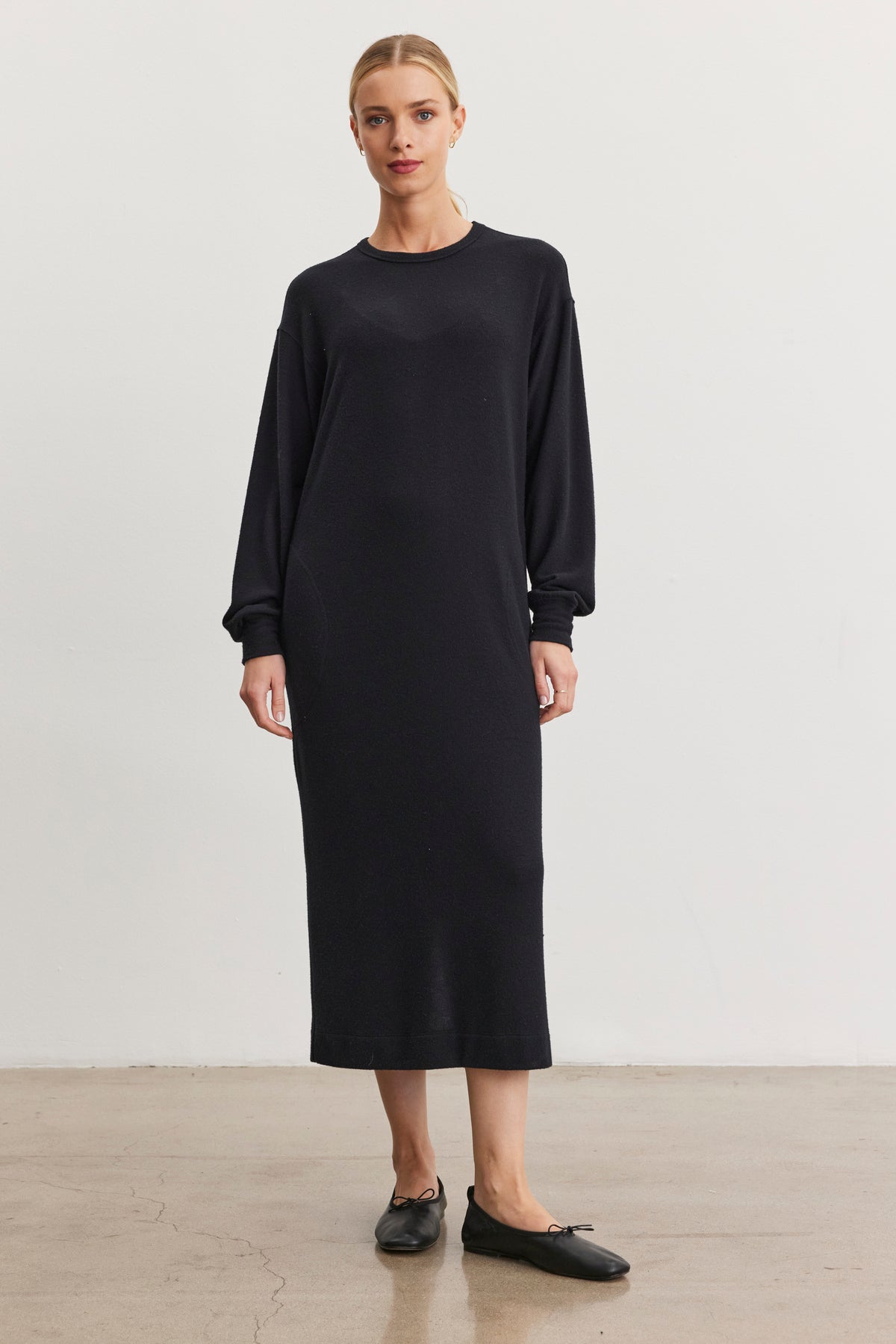 A woman models the AIDA DRESS by Velvet by Graham & Spencer, featuring side seam pockets and a crew neckline, paired with black ballet flats against a plain white background.-38436775592129