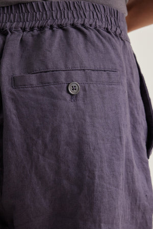 Close-up of a person wearing Velvet by Graham & Spencer’s EAMON LINEN SHORT, featuring lightweight linen, an elastic waistband, buttoned back pocket, and side pocket—ideal for warm weather comfort.