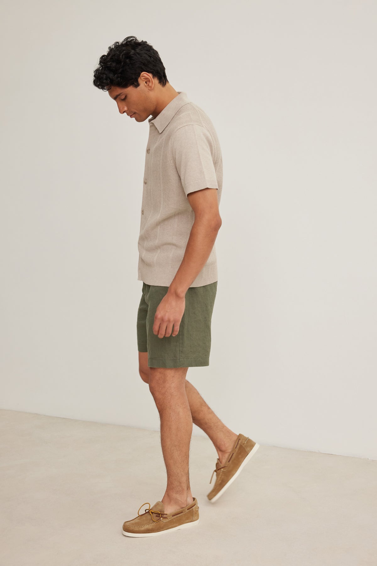 A man stands indoors wearing EAMON LINEN SHORT by Velvet by Graham & Spencer, paired with a beige linen shirt and brown boat shoes, set against a plain light background—ideal for warm weather and versatile style.-39152684728513