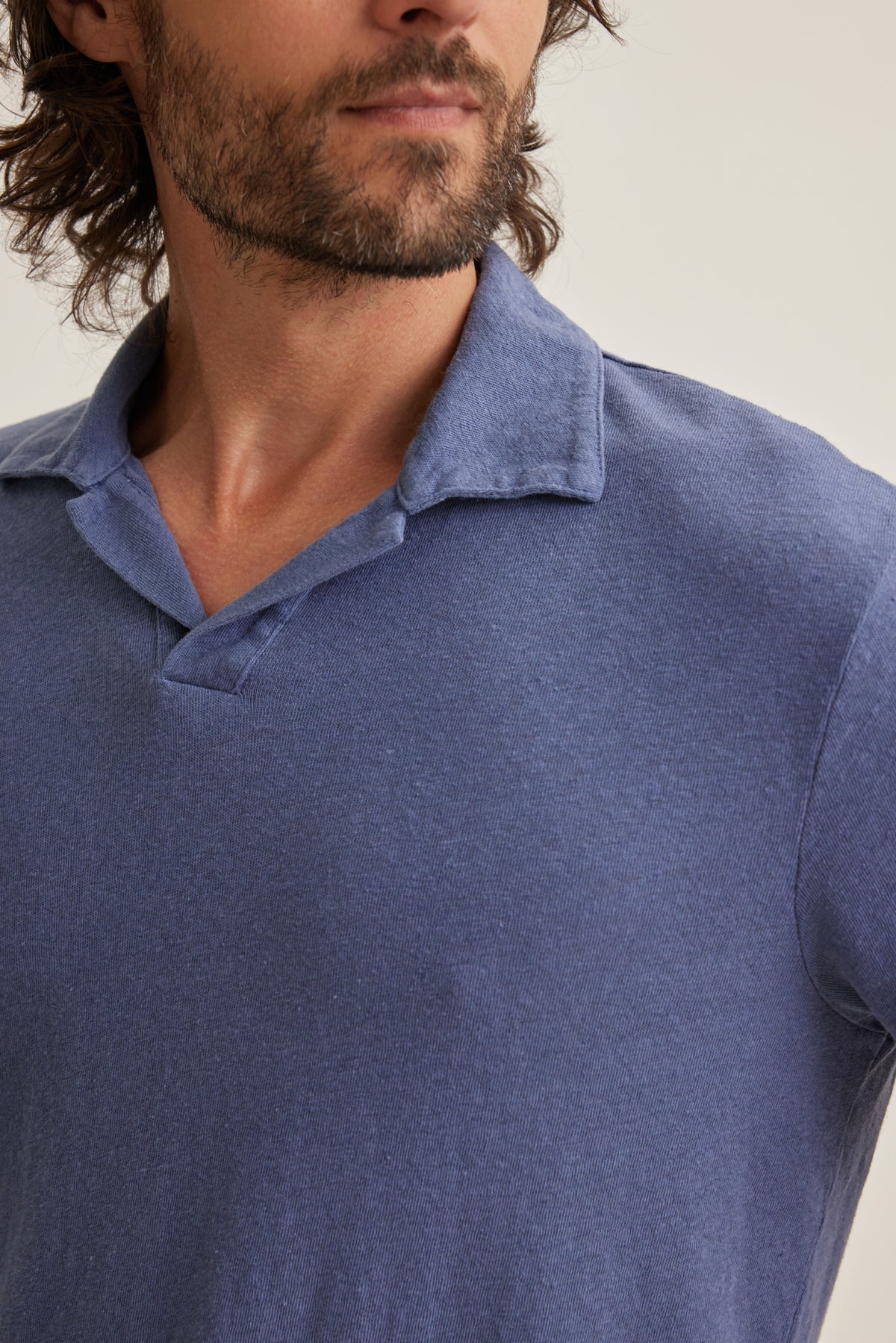 A bearded man wears the BECK LINEN COTTON POLO by Velvet by Graham & Spencer, a blue collared shirt in lightweight linen blend, shown from the shoulders up against a plain background.-39152336404673