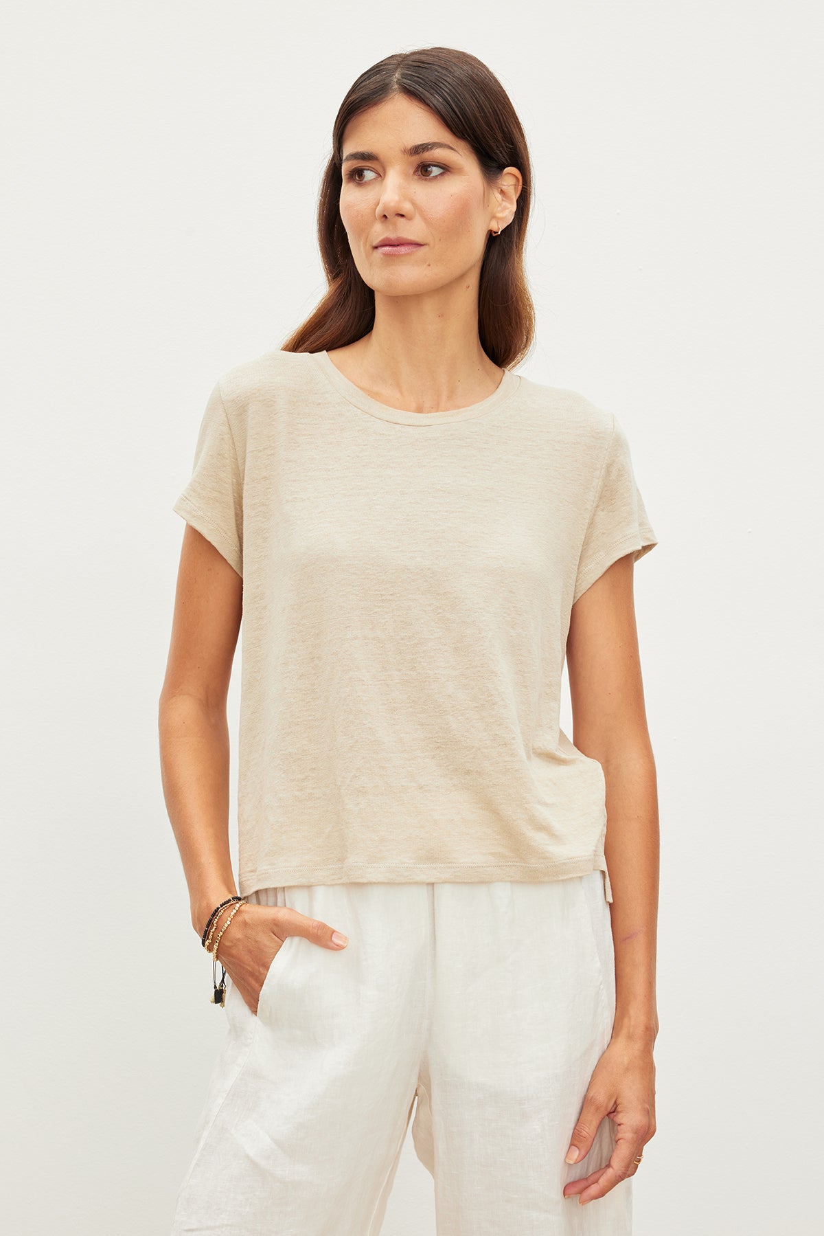   The model is wearing a Velvet by Graham & Spencer beige linen tee and white pants. 