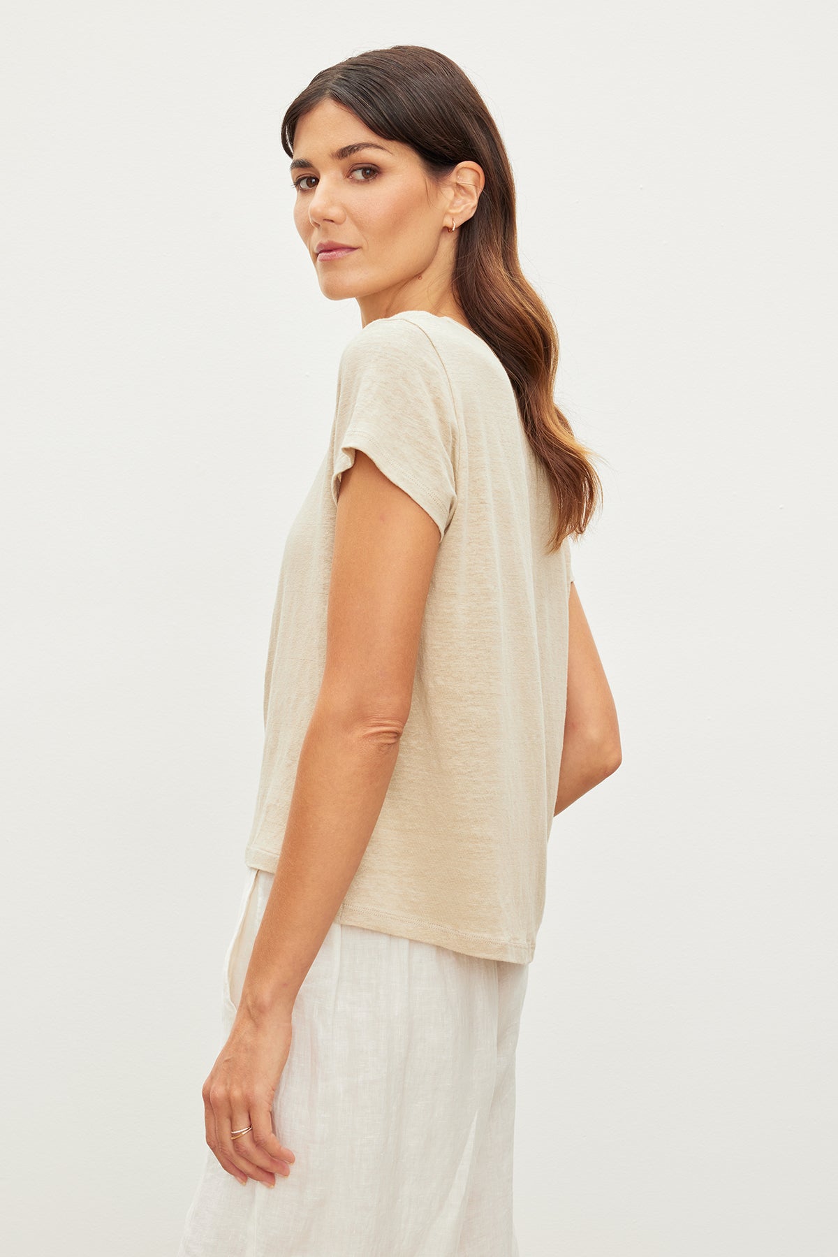   The back view of a woman wearing a Velvet by Graham & Spencer CASEY LINEN KNIT CREW NECK TEE and white pants. 