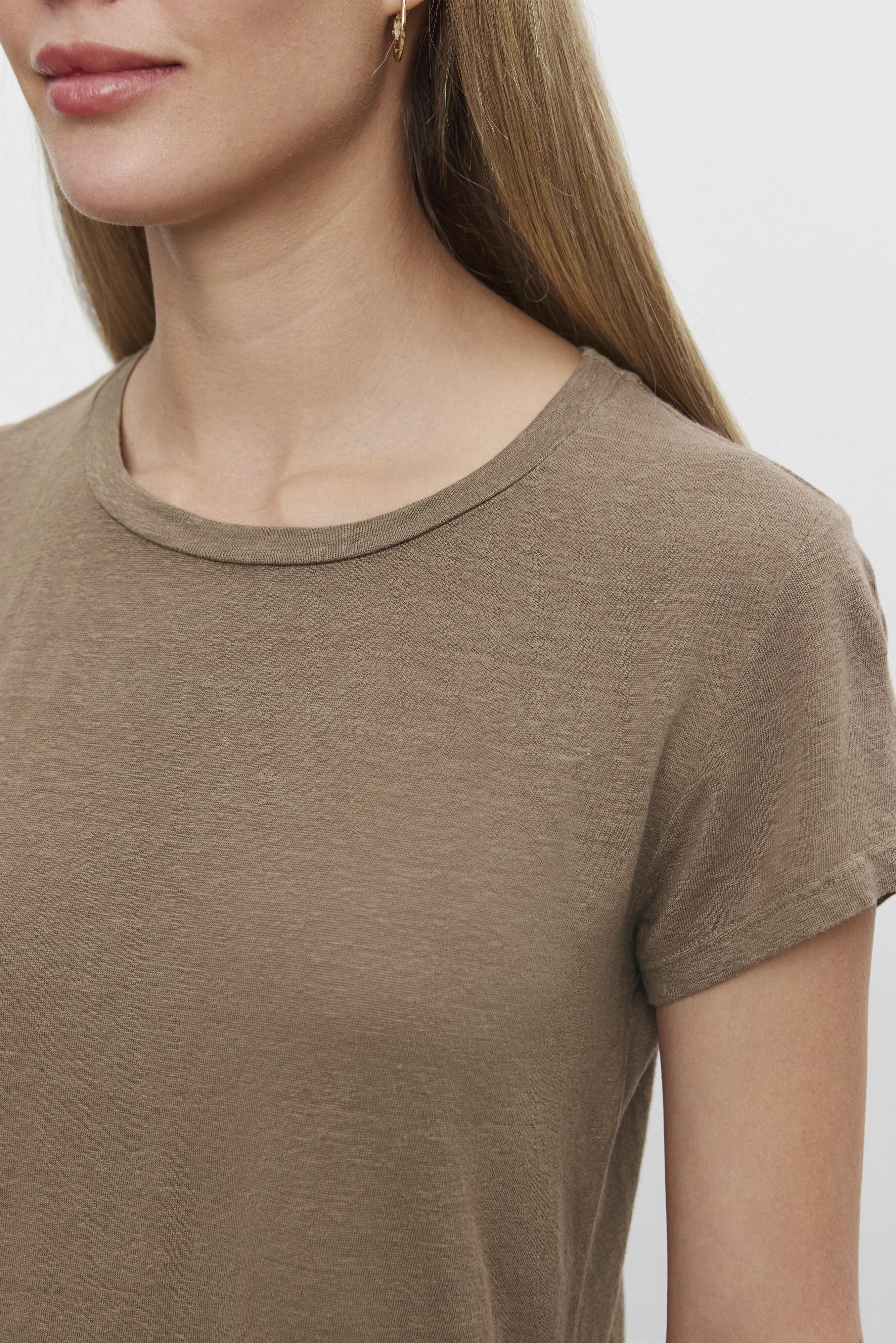   A close-up photo of a woman wearing a Velvet by Graham & Spencer CASEY LINEN KNIT CREW NECK TEE with a hi-lo hemline and a round neckline. 