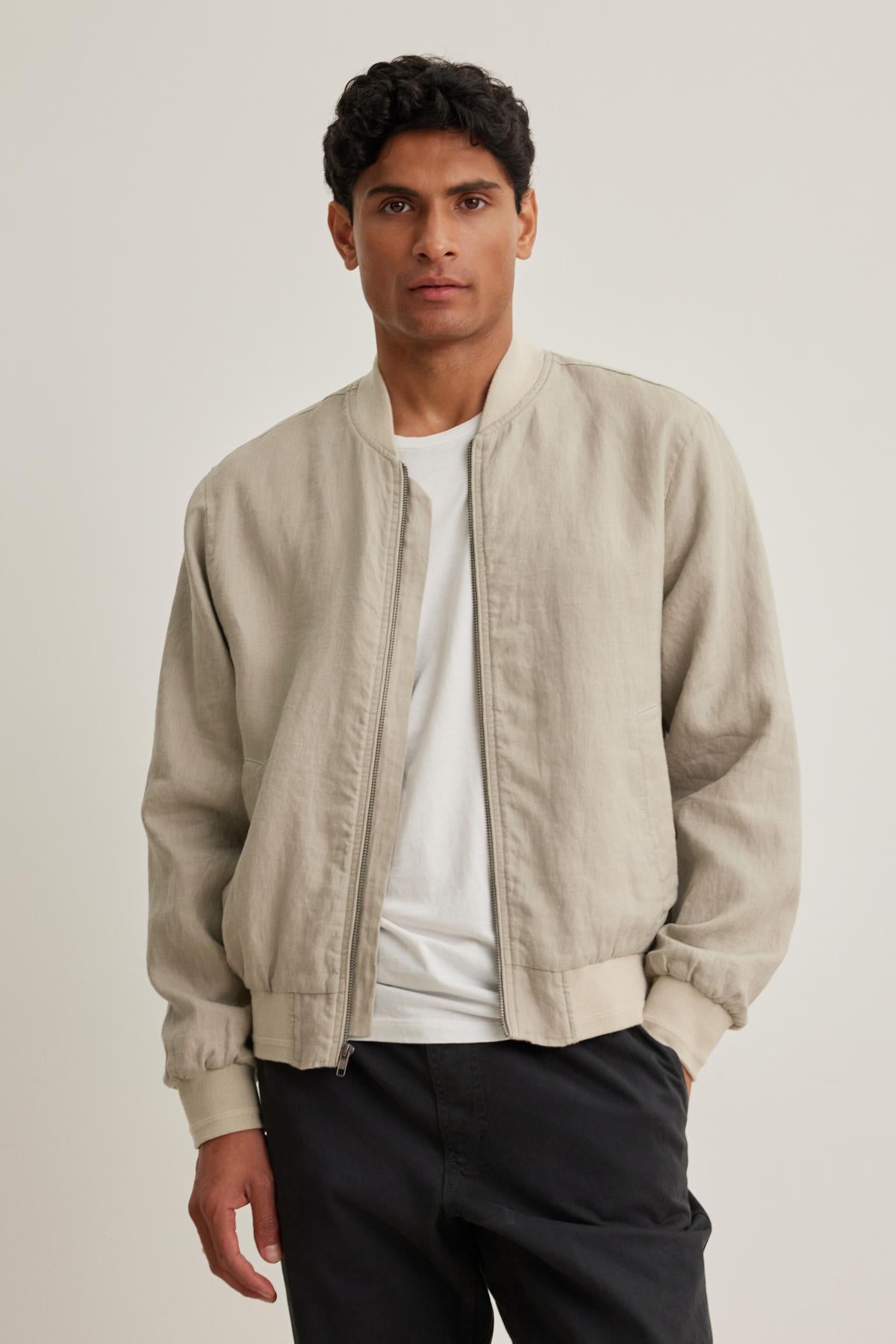 An individual wearing the Murphy Linen Bomber Jacket by Velvet by Graham & Spencer over a white shirt and dark pants stands against a plain background.-38643330580673
