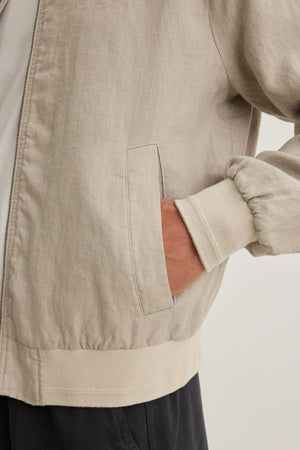 Close-up of a person wearing the MURPHY LINEN BOMBER JACKET by Velvet by Graham & Spencer, with their hand in the pocket.