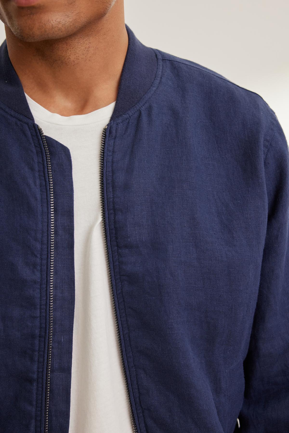 Individual in a Velvet by Graham & Spencer MURPHY LINEN BOMBER JACKET in navy, layered over a white T-shirt, visible from chest to shoulders.