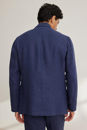 A man wearing the Velvet by Graham & Spencer WARREN LINEN BLAZER is standing with his back facing the camera.