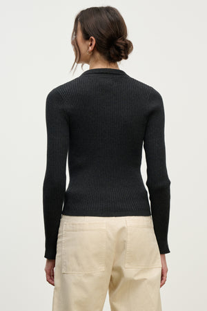 A person with brown hair in a low bun wears the Velvet by Graham & Spencer NIKKI COTTON CASHMERE CARDIGAN and beige pants, shown from the back against a plain light background.