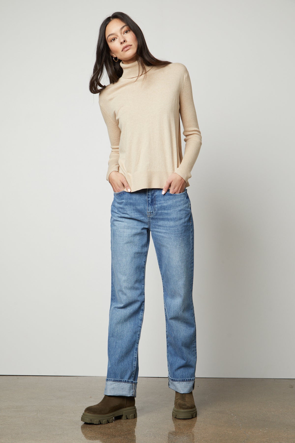 The model is wearing a ribbed beige Velvet by Graham & Spencer SALLY MOCK NECK SWEATER.-35503518843073