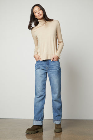 The model is wearing a ribbed beige Velvet by Graham & Spencer SALLY MOCK NECK SWEATER.
